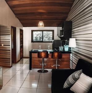 a kitchen with a counter and two stools in a room at Bosque da Praia Chalé 5 in Pipa