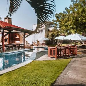 a resort swimming pool with tables and umbrellas at Bosque da Praia Chalé 5 in Pipa