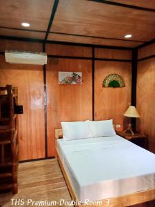 a bed in a room with a wooden wall at Allba's Homestay in Moalboal