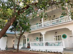 a white house with a balcony and trees at BaywoodGoa in Morjim