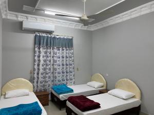 a room with two beds and a ceiling fan at Dar ALHamra Inn in Al Ḩamrāʼ