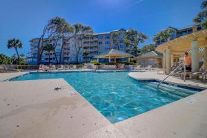 a swimming pool at a resort with chairs and a building at Luxury 2 BR 2 BA Oceanfront Condo King Bed 2 Twins Bikes & Beach Gear included in Hilton Head Island