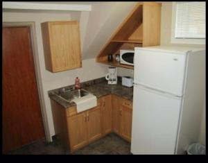 uma cozinha com um frigorífico branco e um lavatório em BUDGET LODGE em Saskatoon
