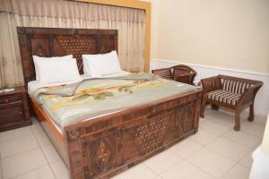 1 cama grande de madera en una habitación con 2 sillas en Stay Inn Guest House, en Karachi