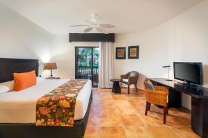 a bedroom with a bed and a desk and a television at Catalonia Riviera Maya Resort & Spa- All Inclusive in Puerto Aventuras