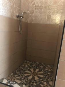 a bathroom with a shower with a tile floor at HOTEL MENABE in Morondava