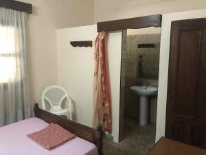 Schlafzimmer mit einem Bett, einem Waschbecken und einem Spiegel in der Unterkunft HOTEL MENABE in Morondava