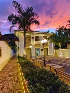 a building with benches and a palm tree at sunset at Pousada Relicário in Tiradentes