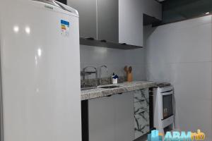 een witte keuken met een spoelbak en een fornuis bij Ed. Manoel Cordeiro - Stúdio Meu aconchego II in Caruaru