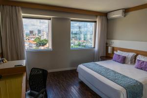 a hotel room with a bed and two windows at Quality Faria Lima in Sao Paulo