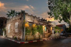 un viejo edificio de piedra con plantas. en Trieste Neve Tzedek Boutique Suites Tel Aviv, en Tel Aviv