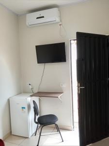 a chair in a room with a television and a refrigerator at Quarto Suíte independente da casa com garagem in Carolina