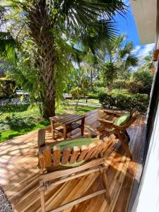 a deck with two chairs and a table and a palm tree at Hotel Cantarana in Playa Grande