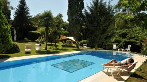 a woman laying on a chair next to a swimming pool at Hotel Villa Clementina in Bracciano
