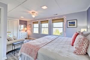 ein Schlafzimmer mit einem Bett, einem Sofa und Fenstern in der Unterkunft Classic Chesapeake Beachside Cottage with Porch! in Norfolk