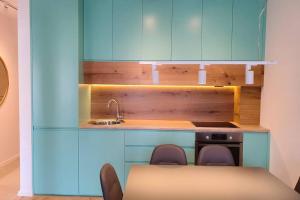a kitchen with blue cabinets and a table and chairs at Luxury Green Apartment in Pristina
