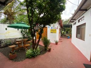 a patio with a table and a green umbrella at Hostal Vista al Mar in Puerto Ayora
