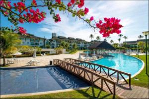 a bridge over a swimming pool in a resort at Beach Class Resort 2 quartos Muro Alto BMS Beira Mar in Porto De Galinhas