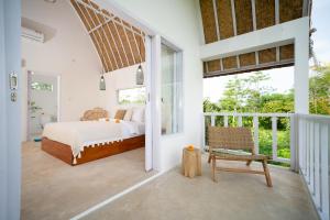 1 dormitorio con 1 cama y 1 silla en el balcón en Kelana Uluwatu en Uluwatu