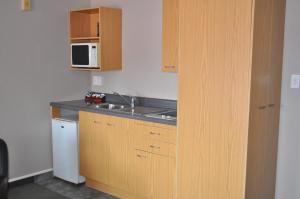 una piccola cucina con lavandino e forno a microonde di City Suites a Tauranga