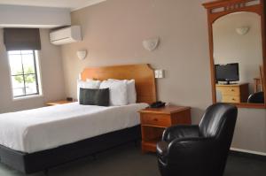 Habitación de hotel con cama y silla en City Suites, en Tauranga