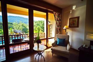 ein Wohnzimmer mit einem Stuhl, einem Tisch und einem Balkon in der Unterkunft Belle Villa Resort, Chiang Mai in Ban Pong