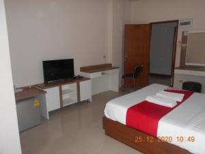 a bedroom with two beds and a desk with a television at Purada Mansion Bangsaen in Ban Hua Laem