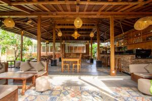 Una sala de estar abierta con barra y mesas. en Moson Villa Legian, en Legian