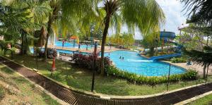 ein großer Swimmingpool mit Palmen in einem Park in der Unterkunft Homestay 3 rooms suite Apartment 8-10pax at Amari Villa Bukit Katil, Ayer Keroh Melaka in Malakka