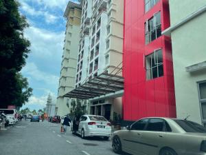 ein rotes Gebäude an der Seite einer Straße mit Autos in der Unterkunft Homestay 3 rooms suite Apartment 8-10pax at Amari Villa Bukit Katil, Ayer Keroh Melaka in Malakka