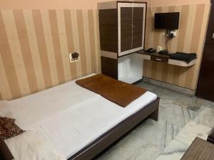 ein Schlafzimmer mit einem Bett und einem Schreibtisch mit Fernseher in der Unterkunft Hotel Prince in Guwahati