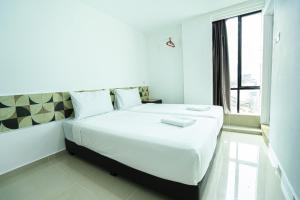 a bedroom with a large white bed with a window at Grand Bagan Hotel in Butterworth