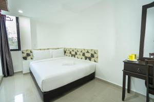 a bedroom with a white bed and a night stand at Grand Bagan Hotel in Butterworth