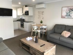 uma sala de estar com um sofá e uma mesa em Rose Apartments Central Rotorua- Accommodation & Private Spa em Rotorua
