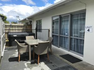 Rose Apartments Central Rotorua- Accommodation & Private Spa في روتوروا: فناء على طاولة وكراسي على شرفة