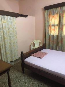 ein Schlafzimmer mit einem Bett, einem Stuhl und Vorhängen in der Unterkunft HOTEL MENABE in Morondava