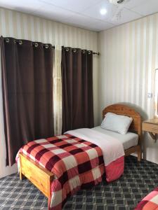 a bedroom with a bed with a checkered blanket at Madina Hotel 2 in Gilgit