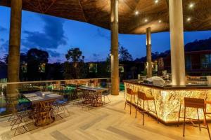 拷叻的住宿－Kalima Resort and Villas Khao Lak - SHA EXTRA PLUS，一个带桌椅的庭院和一间酒吧