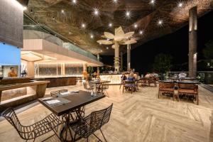 Kalima Resort and Villas Khao Lak - SHA EXTRA PLUS في خاو لاك: مطعم بطاولات وكراسي وبار