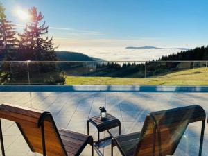 a patio with two benches and a table with a view at Hotel Tetřeví Boudy in Pec pod Sněžkou