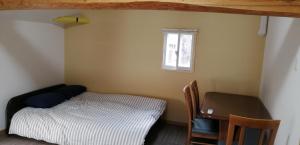 高松市にあるkaeru Guest houseのベッドルーム1室(ベッド1台、デスク、窓付)