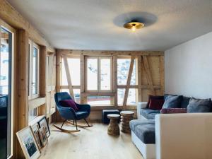 a living room with a blue couch and chairs and windows at Chalet Bergheimat Zermatt in Zermatt