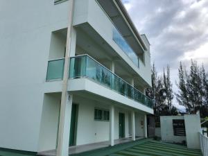 a white building with a balcony on the side at Residencial Esmeralda-Vista ao Mar in Palhoça