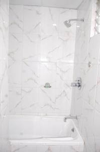 a bathroom with a shower with white marble tiles at Hotel Vice President in Ahmedabad