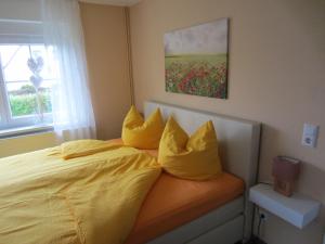 um quarto com uma cama com lençóis e almofadas amarelas em Ferienhaus zum Nautzschketal mit Fewo Uta und Fewo Regina em Gröbitz