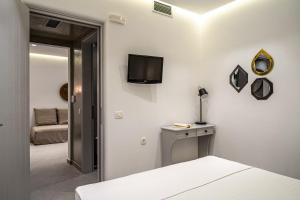 a bedroom with a bed and a television on a wall at Hippocampus Hotel in Kamari