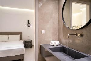 a bathroom with a sink and a bed and a mirror at Hippocampus Hotel in Kamari