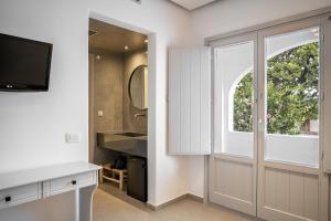 a bathroom with a sliding glass door and a television at Hippocampus Hotel in Kamari