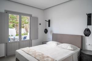 a white bedroom with a bed and a window at Hippocampus Hotel in Kamari