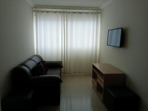 sala de estar con sofá negro y TV en Apartamento frente ao mar, en Balneário Camboriú
